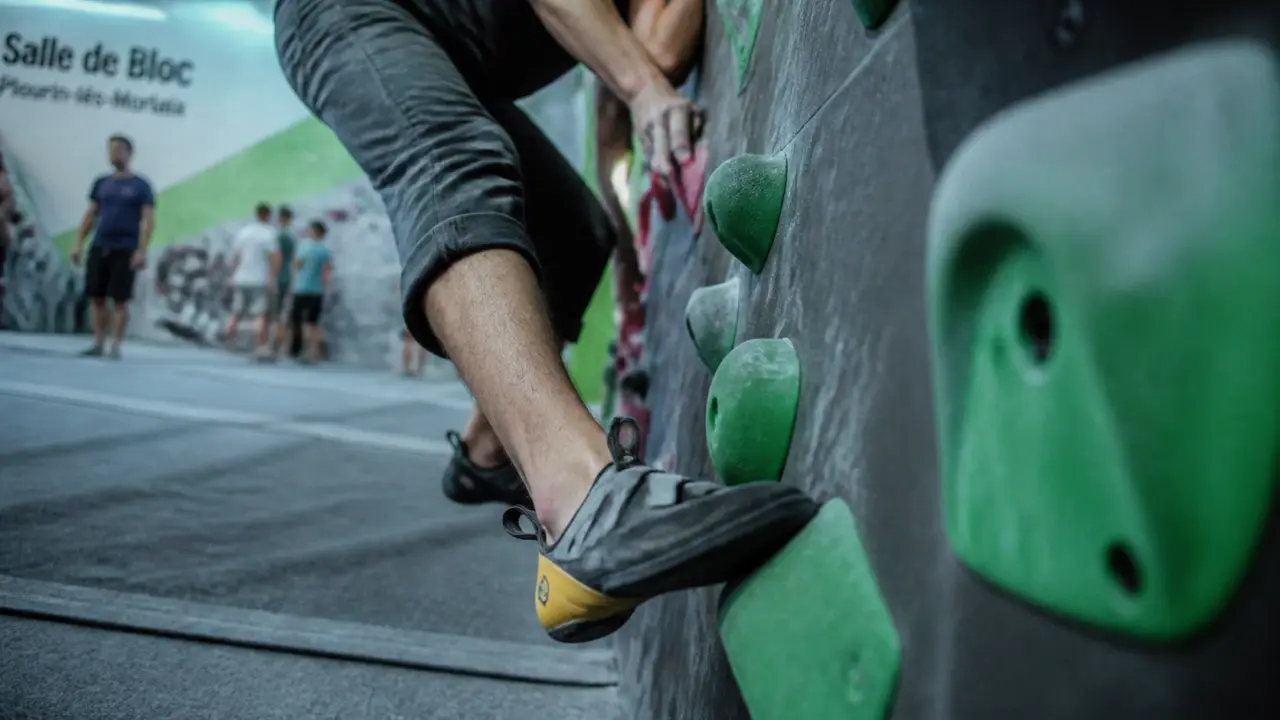 Salle de bloc Plourin-les-Morlaix : grimpeur en salle, mur et tapis épais